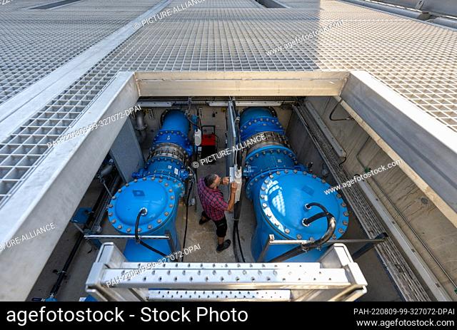 09 August 2022, Saxony, Grimma: An employee of the Grimma river maintenance department stands between pumps in the pumping station on the Mulde River in Grimma