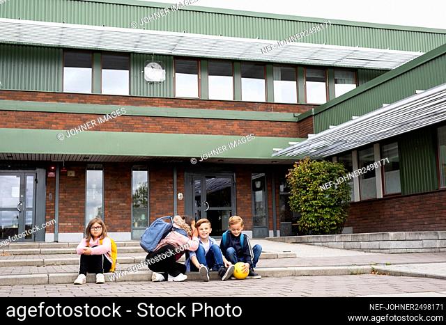 Children sitting in front of school building