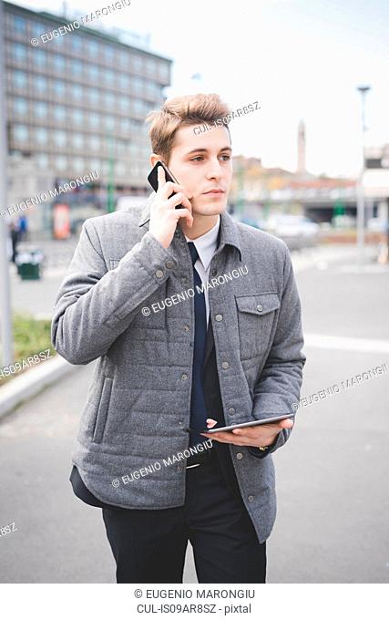 Portrait of young businessman using digital tablet and mobile phone