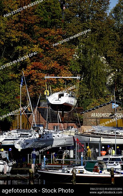 PRODUCTION - 22 October 2023, Mecklenburg-Western Pomerania, Rostock: Sailors from the Academic Sailing Association in Rostock-Gehlsdorf crane their sport boats...