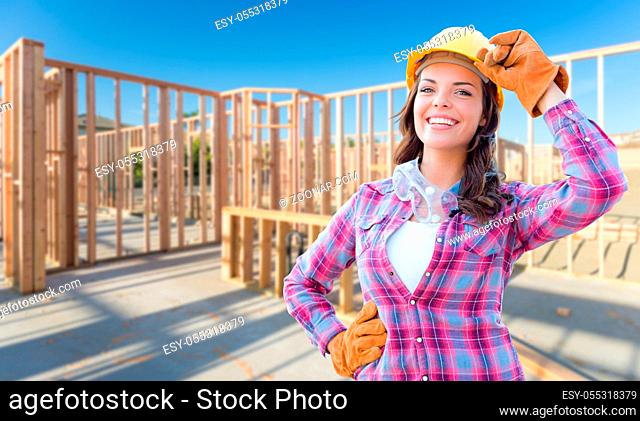 Young Attractive Female Construction Worker Wearing Gloves, Hard Hat and Protective Goggles At Construction Site