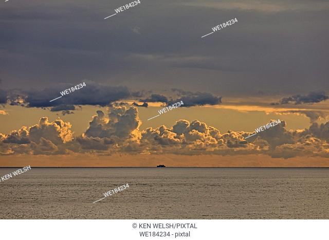 Cloudy dawn with ship on horizon