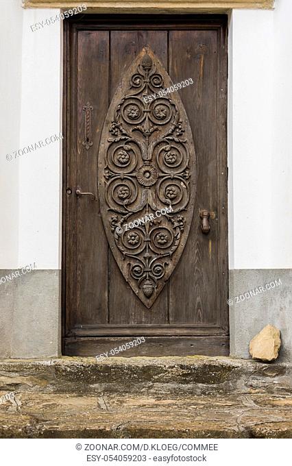 Old carved wooden and crooked door in Montechiaro d'Acqui, Piedmonte, Italy