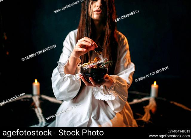Young woman in white shirt sitting in the center of pentagram circle with candles and produces a ritual of black magic, black wooden floor