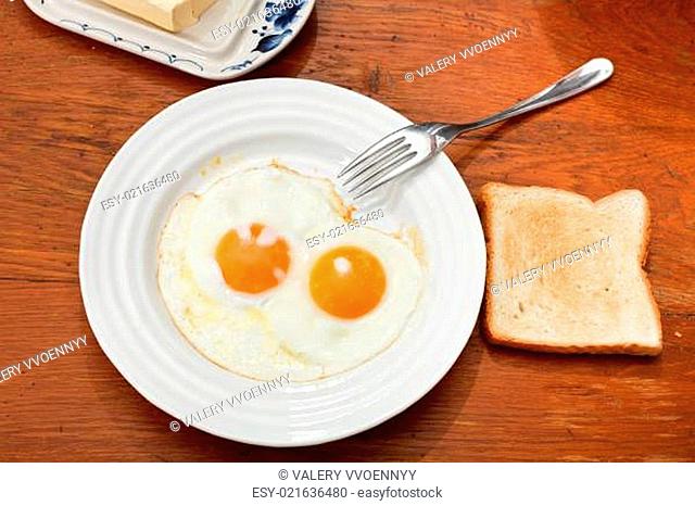 breakfast with two fried eggs in white plate