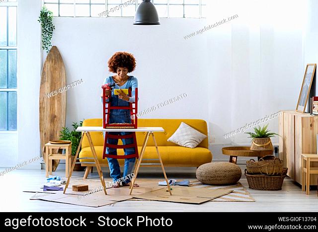 Afro woman using mobile phone in living room