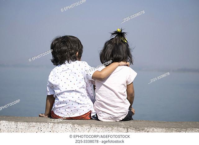 Boy and little girl sitting near lake, Veer dam, Pune, Maharashtra, India