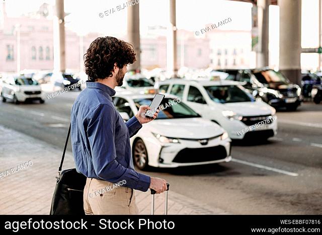 Businessman using smart phone standing at footpath