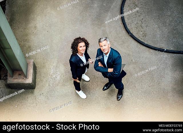 Confident businessman standing by colleague on floor in industry