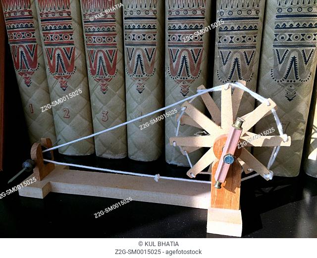 Books by Gandhi on a shelf with his symbolic spinning wheel, Ontario, Canada