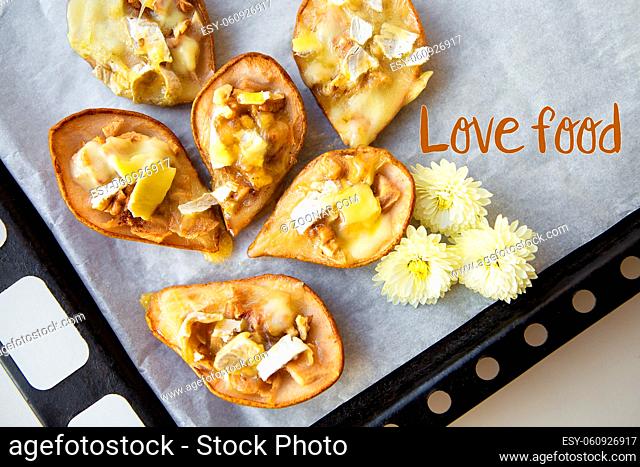 baked pears with brie cheese and walnuts lie on a baking-inscription love food