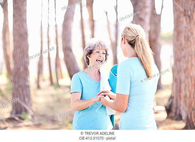 Senior woman and yoga instructor talking in sunny park