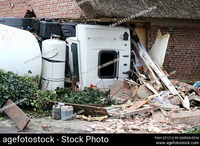 12 December 2023, Schleswig-Holstein, Blomesche Wildnis: A concrete mixer lies on its side after crashing into a house. A multi-axle concrete mixer with a total...