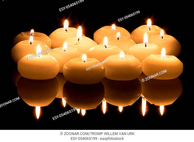 White candles on a black reflecting background