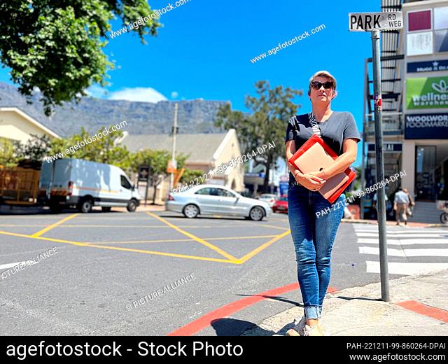 PRODUCTION - 03 November 2022, South Africa, Kapstadt: Christina Leitner is standing at an intersection in Cape Town with her laptop