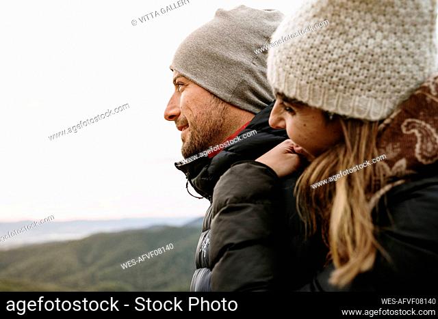 Smiling couple in warm clothing looking away during winter