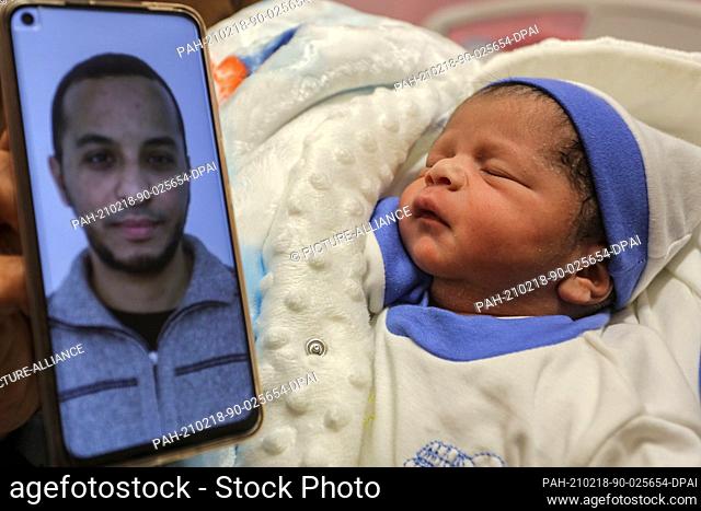 18 February 2021, Palestinian Territories, Khan Yunis: A picture of Palestinian prisoner Muhammad al-Qudra is shown on a mobile phone next to his new born baby...