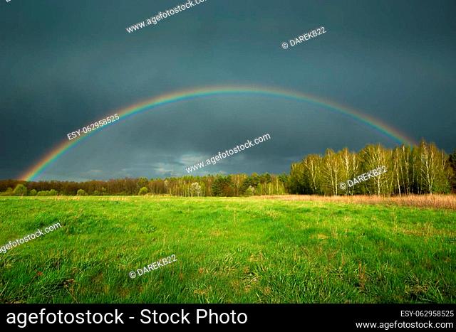 View of a rainbow with a rainy dark cloud, spring day