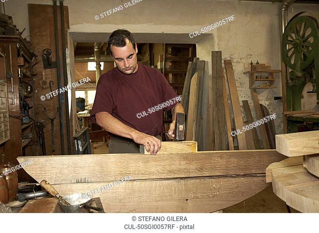 Worker hammering wood in shop