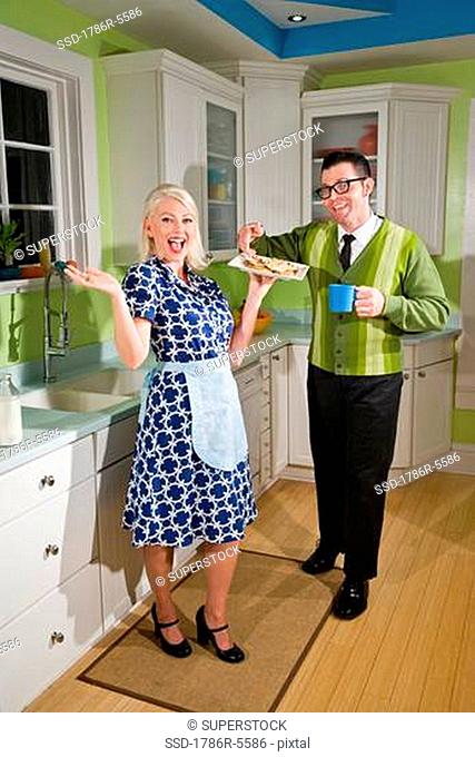 Retro couple at home in kitchen eating cookies