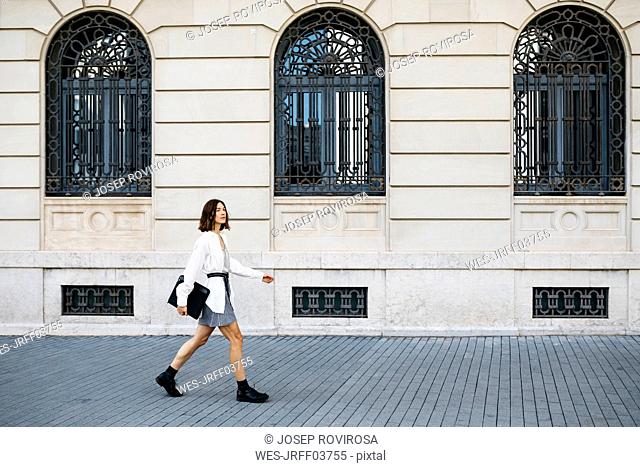 Well dressed woman carrying folder, walking in the city