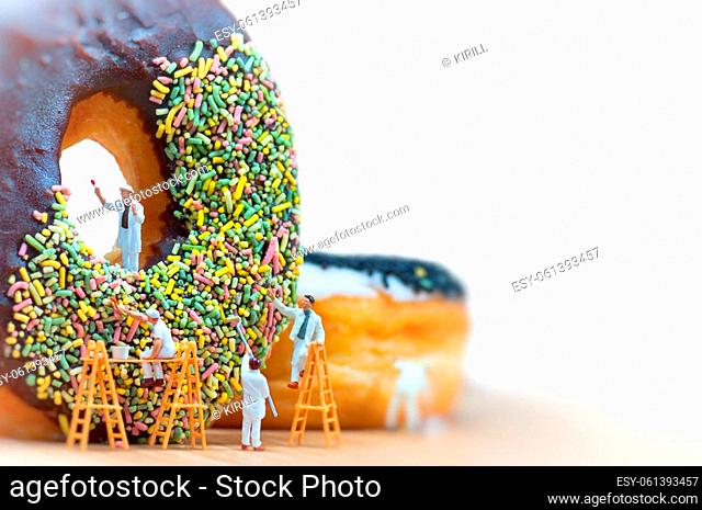 Group of painters painting over huge donut. Macro photo