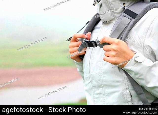 Close up of a hiker hands catching backpack ready to walk in the mountain a foggy day