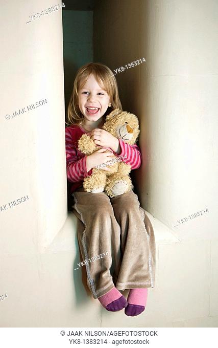 Three Year Old Girl Sitting in Stove Recess With Teddy Bear