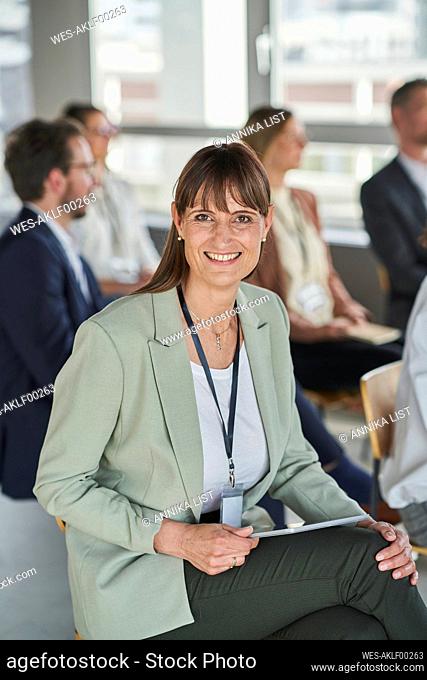 Businesswoman smiling while sitting with colleagues in conference centre