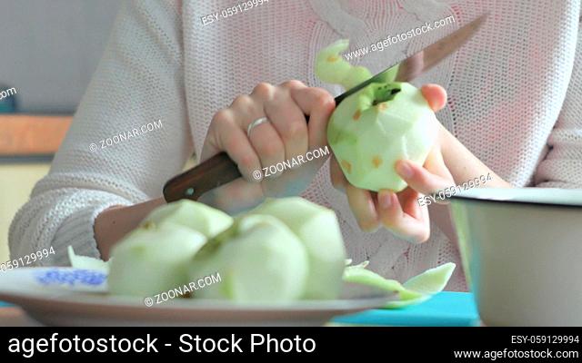 A woman peeled an apple on a plate Woman clears the table. prepares bread or apple pie