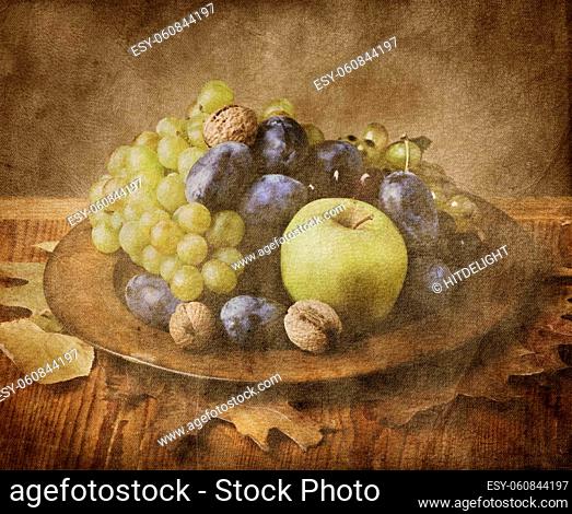 Autumn fruit in wooden plate on grungy background