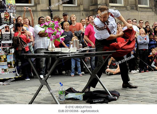 Fringe Festival of the Arts 2010 Street performers and crowds on the Royal Mile magaician pulling table cloth from under plates