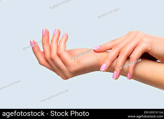 Beautiful woman hands with french manicure. Over light grey background. Copy space