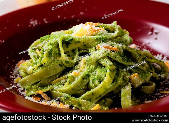 fresh green vegetarian tagliatelle dish in red plate