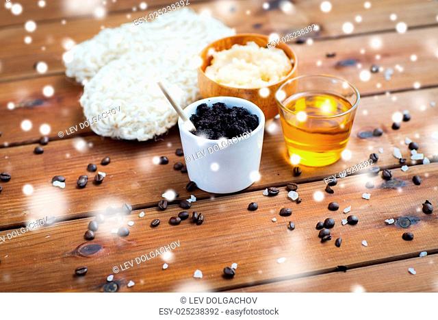 beauty, spa, bodycare, bath and natural cosmetics concept - homemade coffee scrub in cup with wisp and honey on wooden table over snow