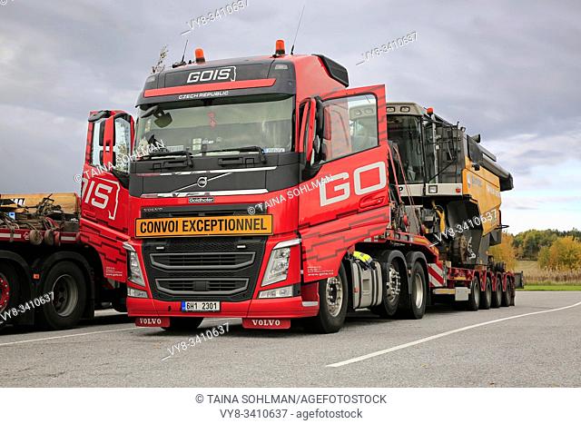 Red Volvo FH semi truck Gois Logistics for oversized load transport of a Sampo Rosenlew 3085L combine on truck stop in Salo, Finland. October 6, 2019