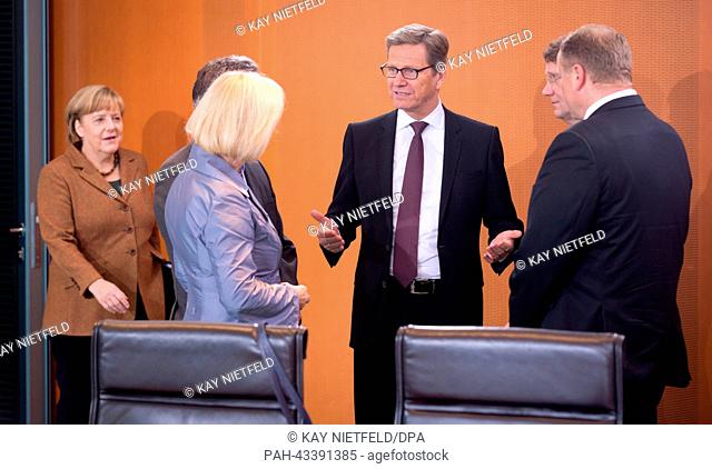 German Chancellor Angela Merkel (L) arrives to a meeting of her cabinet while out-going Foreign Minister Guido Westerwelle (C) talks with Education Minister...