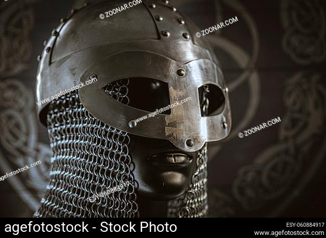 Viking helmet with chain mail of iron on red shield of wood and golden triskel