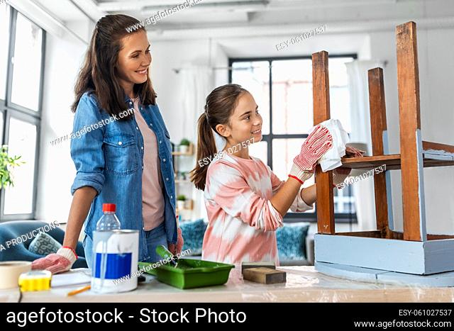 mother and daughter cleaning old wooden table