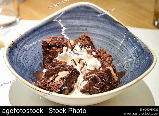 Delicious chocolate brownie dessert with cream on modern ceramic plate