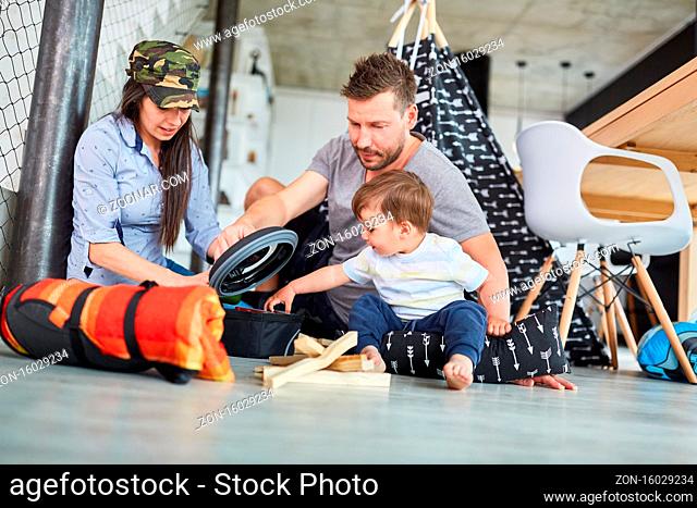 Eltern spielen Camping und Outdoor Survival Training mit Kleinkind im Wohnzimmer