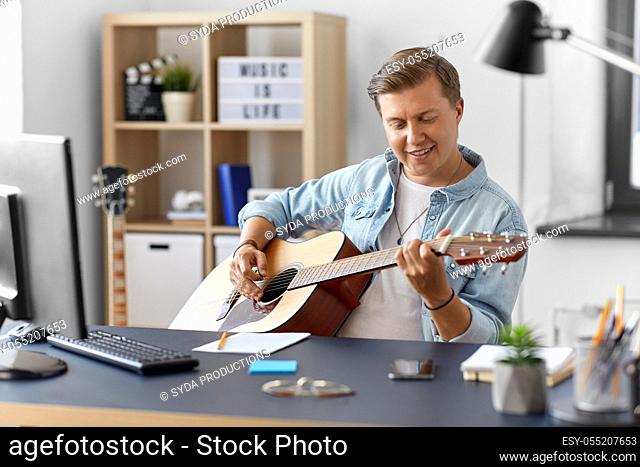young man playing guitar sitting at table at home