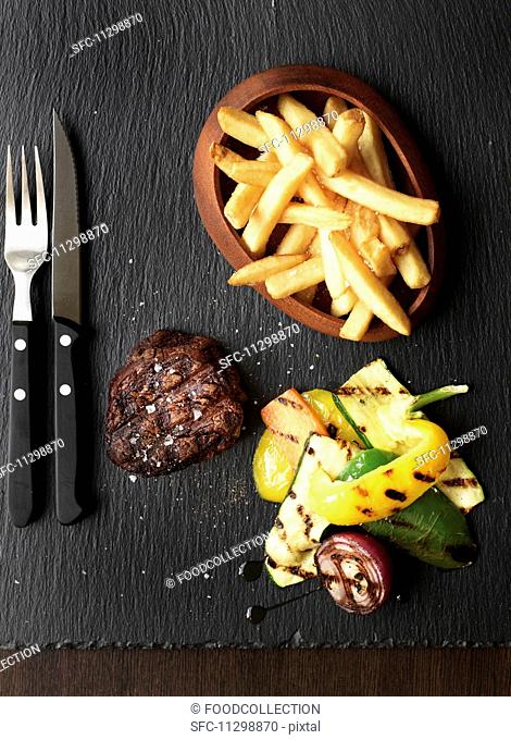 Grilled beef steak with chips and grilled vegetables