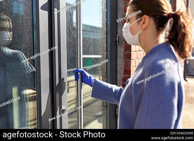 woman in mask and glove trying to open door