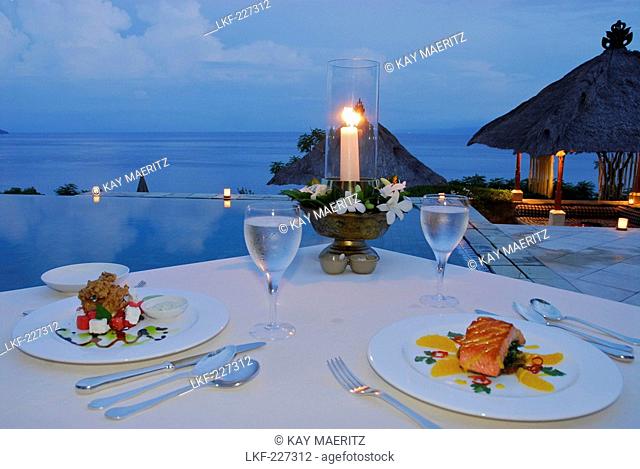 A table is laid at the pool at Amankila Resort in the evening, Candi Dasa, Eastern Bali, Indonesia, Asia