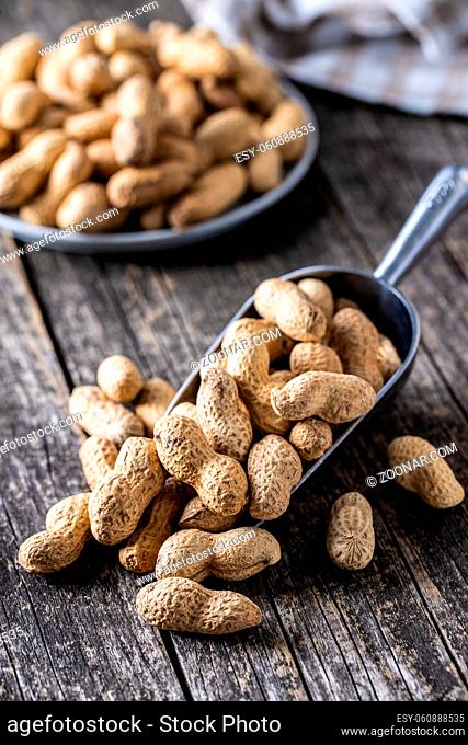 Roasted peanuts. Tasty groundnuts in metal scoop on wooden table