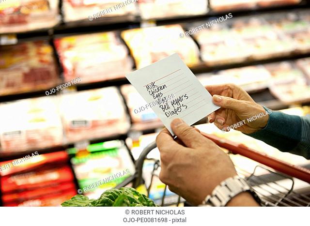 Older woman reading grocery list in supermarket