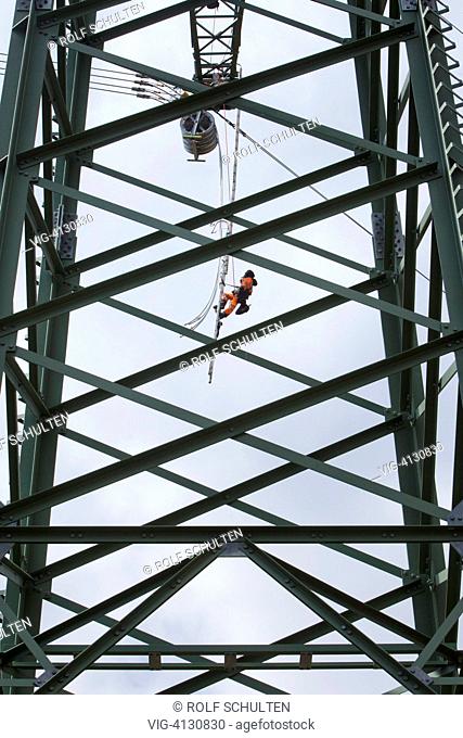 GERMANY, MOENCHENHOLZHAUSEN, : Cable riggers at work on a newly built transmission tower that is run by transmission system operator 50Hertz