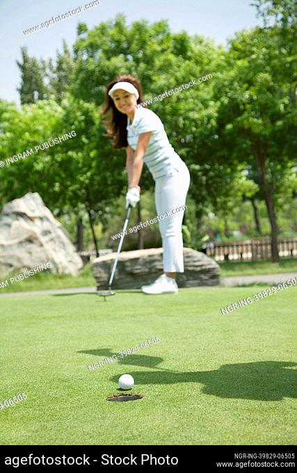 Young woman hitting the ball on the golf course