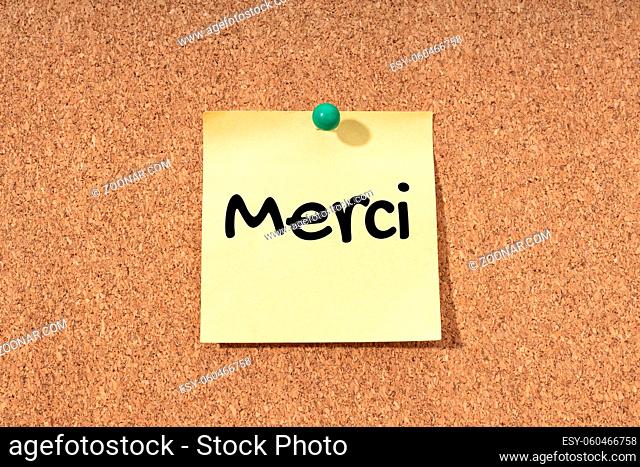 Thanks word in french language on yellow note on cork board